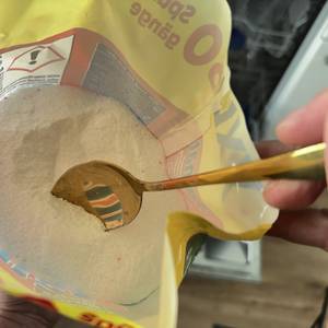Ein Löffel entnimmt etwas Spülmaschinenpulver der Marke Somat.