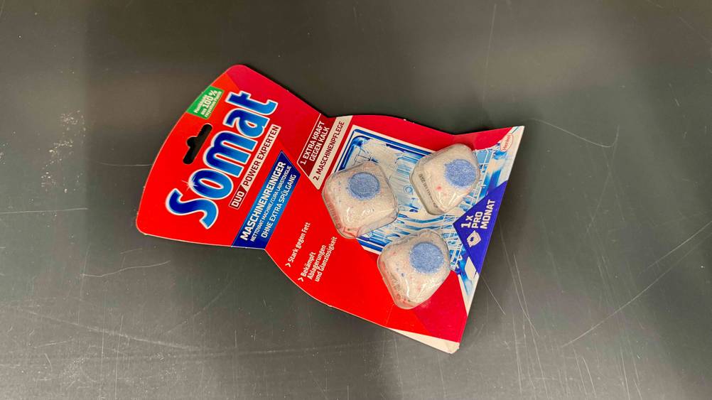 Auf einer grauen Fläche befindet sich eine Packung der gestesteten Somat-Tabs.