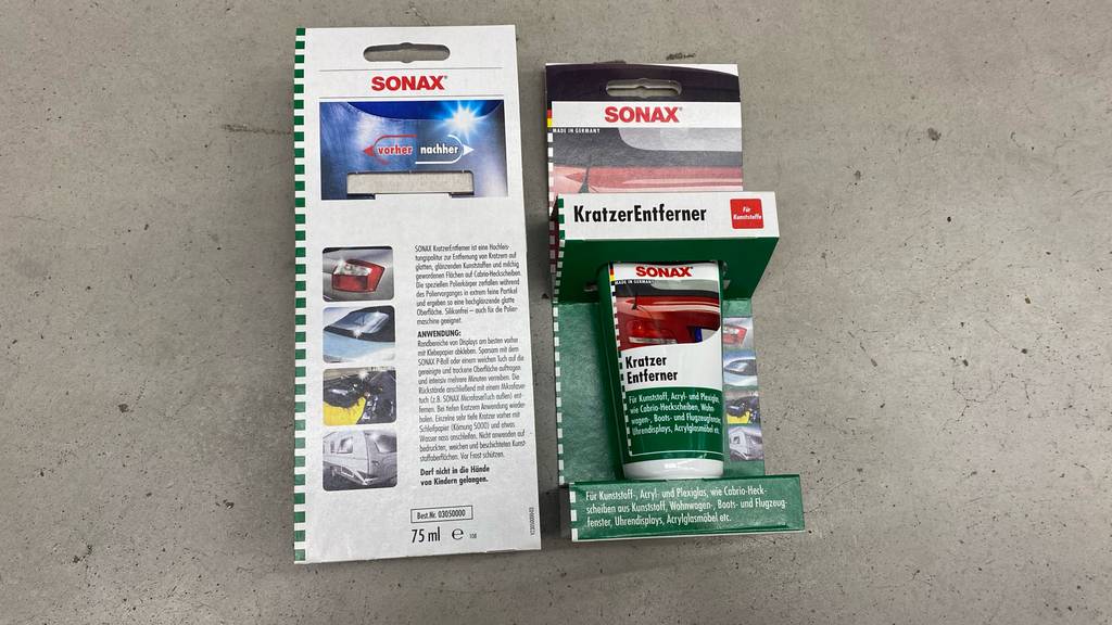 Auto-Kratzer-Entferner getestet: zwei Sonax-Verpackungen mit vorderer und rückwärtiger Ansicht liegen auf einer grauen Oberffläche.