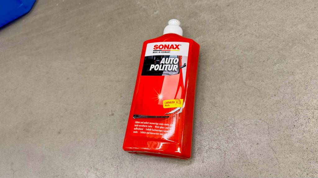Eine Flasche getestete Sonax-Politur liegt auf einem grauen Boden.