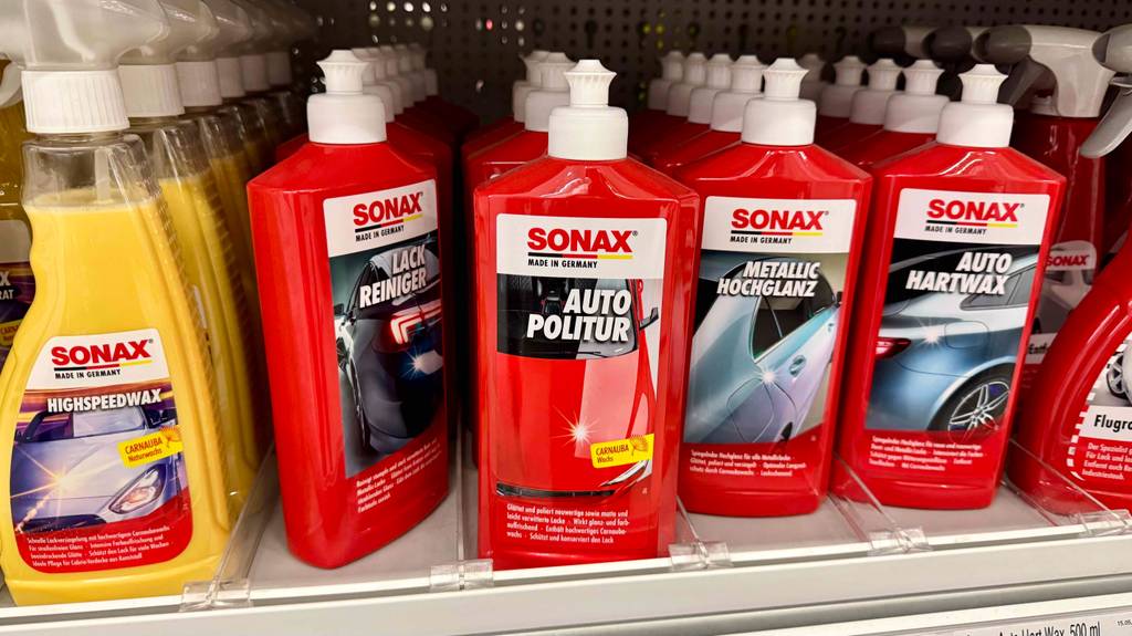 Sonax-Politur im Test: Mehrere Flaschen stehen zwischen anderen Reinigungsprodukten in einem Regal.