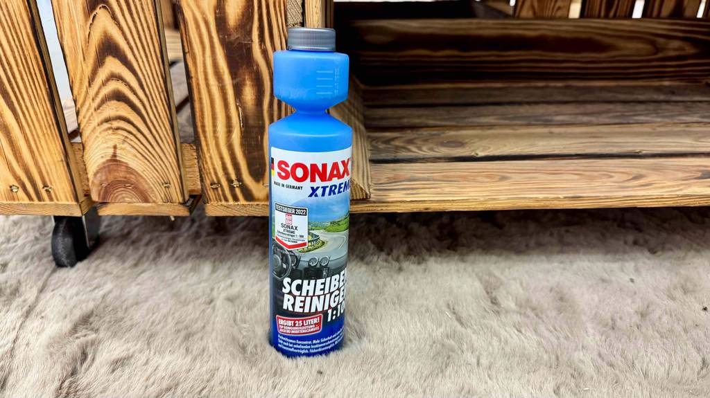 Getestet: Scheibenreiniger-Konzentrat 1:100 in der Flasche von Sonax steht vor einer Holzbox.