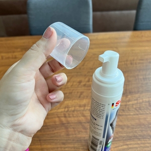 Eine Hand hält den Deckel des Sonax XTREME Polsterreiniger neben die Flasche.