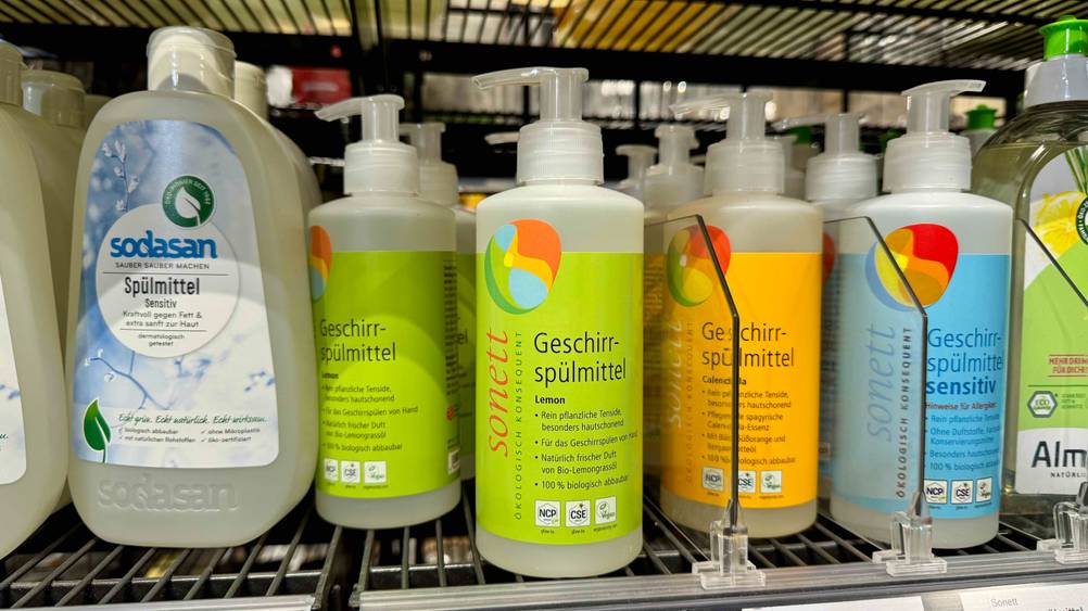 Mehrere Flaschen des getesteten Sonett-Geschirrspülmittel in einem Verkaufsregal neben anderen Produkten.