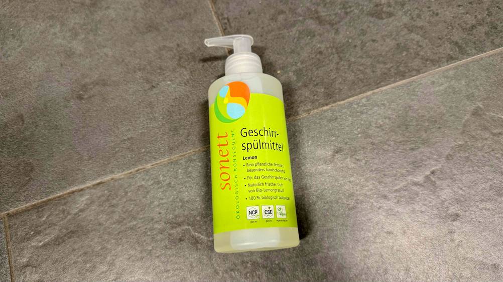 Eine Flasche des getesteten Sonett-Geschirrspülmittels liegt auf einem grauen Fließenboden.
