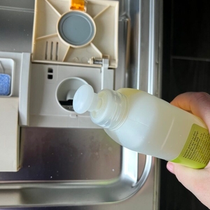 Eine Hand gießt Sonett-Klarspüler in den dafür vorgesehenen Einlass