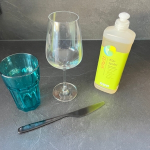 Der Sonett-Klarspüler steht neben einem Messer, einem Glas und einem Weinglas