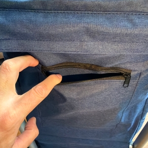 Eine Hand öffnet eine Tasche mit Reißverschluss am Songmics KST02GY.