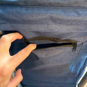 Eine Hand öffnet eine Tasche mit Reißverschluss am Songmics KST02GY.