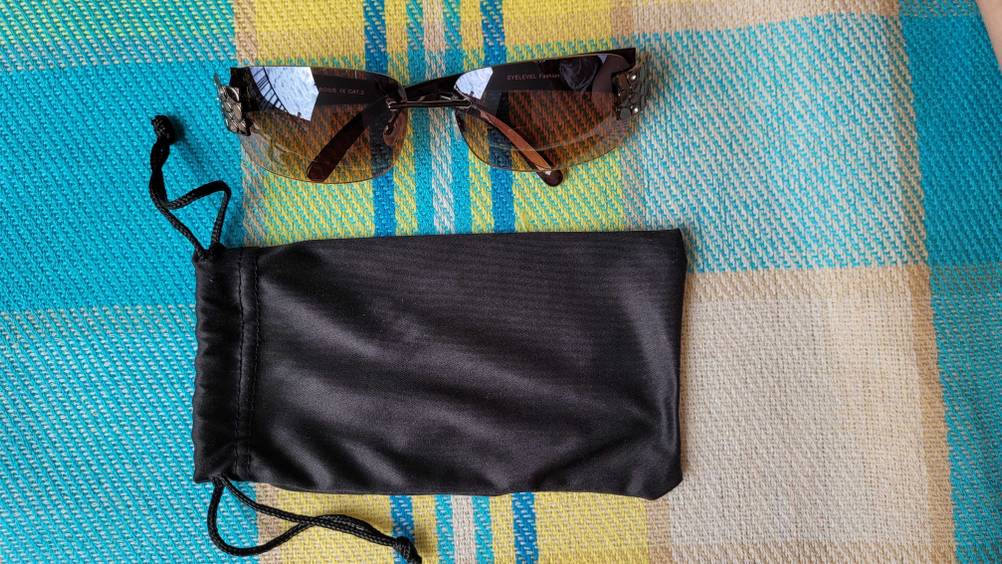 Eine Damen-Sonnenbrille im Test über ihrer Schutzhülle liegend auf einer bunten Tischdecke.