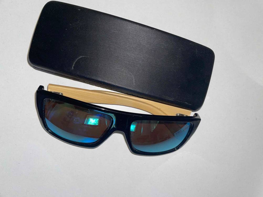 Herren-Sonnenbrille getestet: Eine Brille neben einem Brillenetui von oben auf einer hellen Fläche.