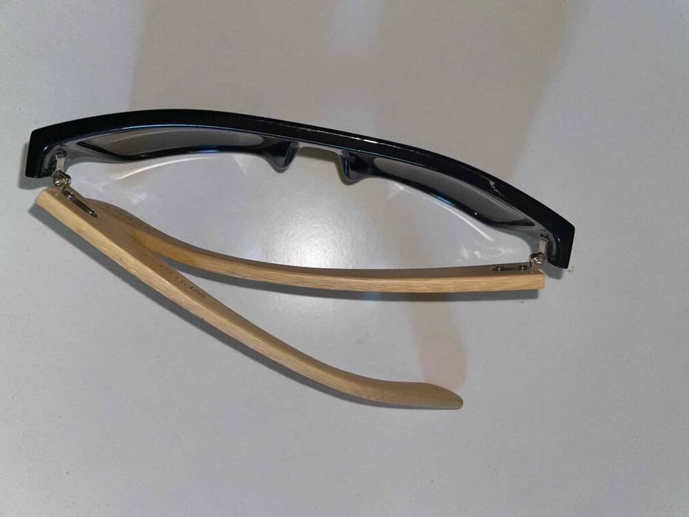 Eine getestete Herren-Sonnenbrille von oben auf einer hellen Fläche liegend.