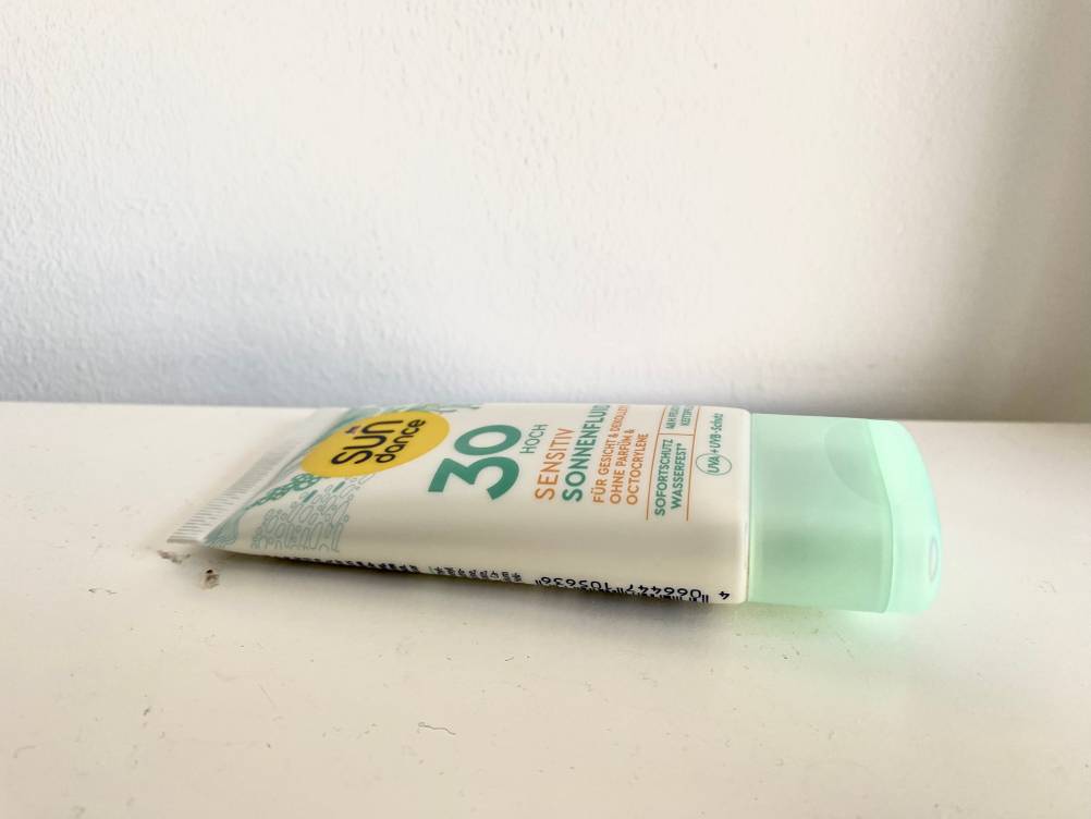 Eine Tube Gesichts-Sonnencreme im Test von der Seite auf einer hellen Fläche liegend.
