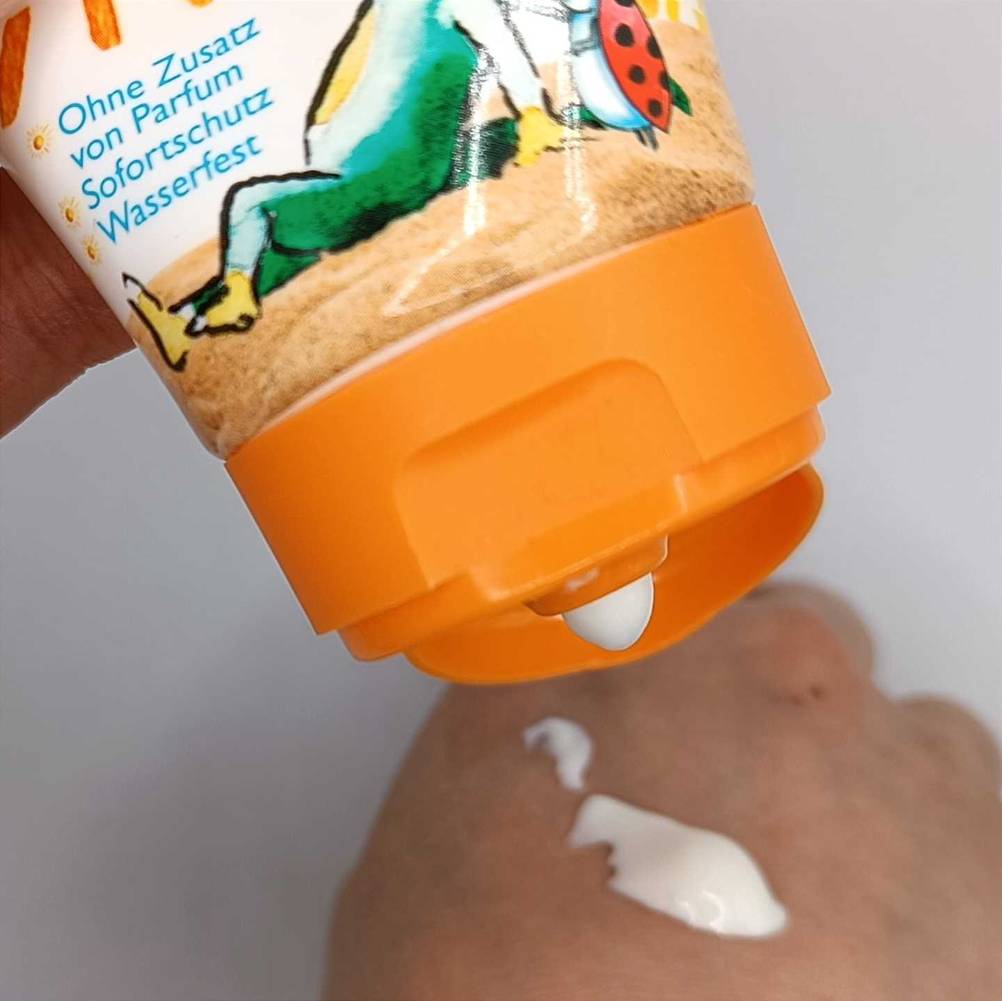Kinder-Sonnencreme getestet: Nahaufnahme des geöffneten Verschlusses aus dem Creme auf einen Handrücken gedrückt wird.