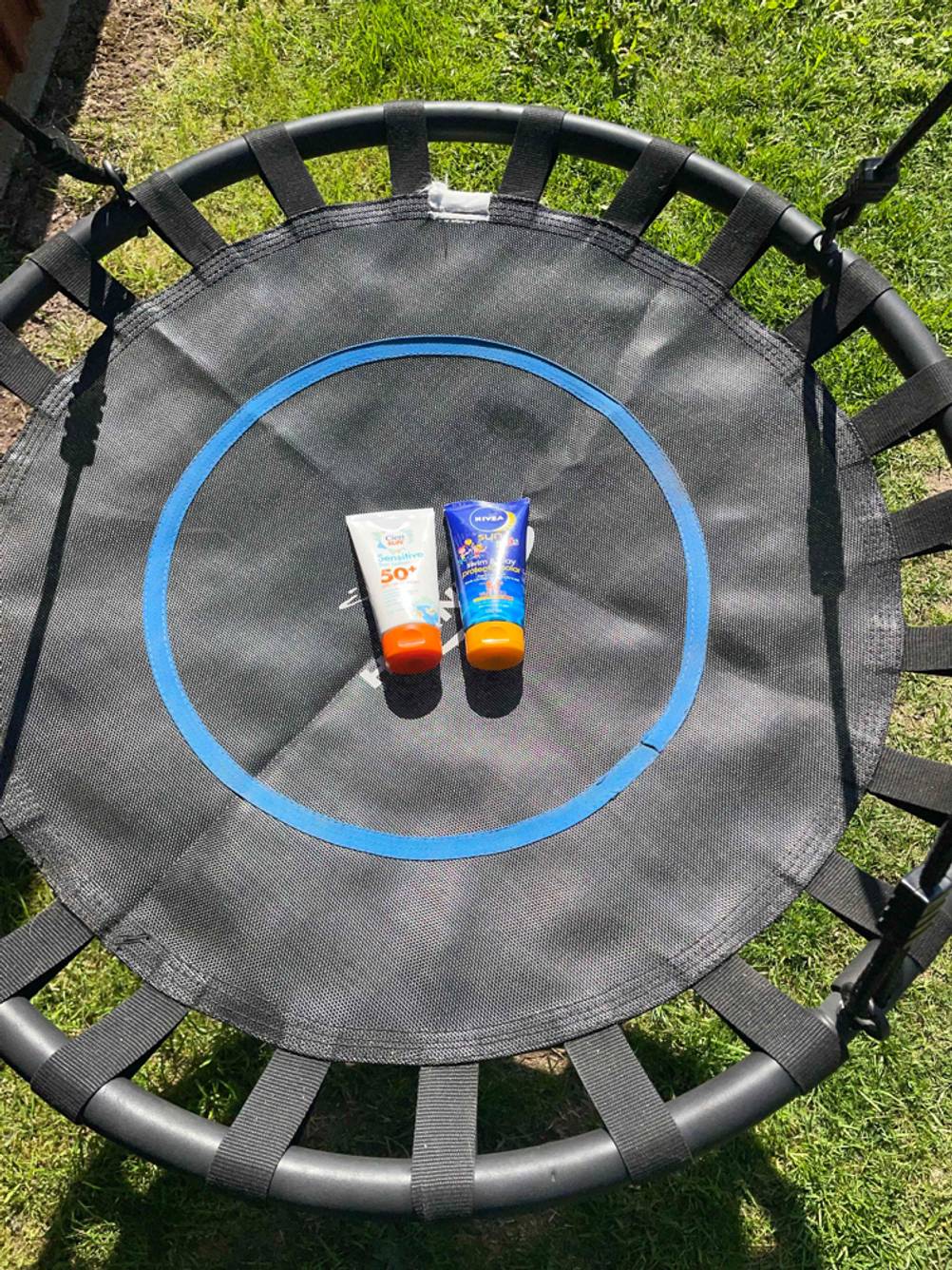 Auf einem Trampolin liegen zwei getestete Sonnencremes mit LSF 50.