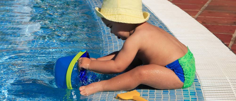 Sonnenhut-Herren-Test: Ein Baby mit einem Sonnenhut spielt am Pool.