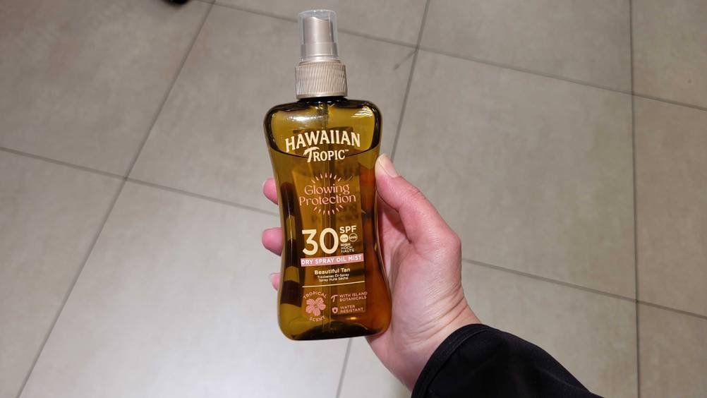 Eine Hand hält das Sonnenöl im Test hoch.