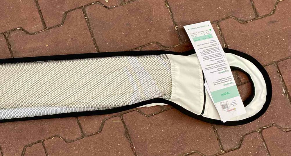 Nahaufnahme der Verpackung und des Infolabels eines getesteten Sonnenschirm (200 cm) auf einem Steinboden.