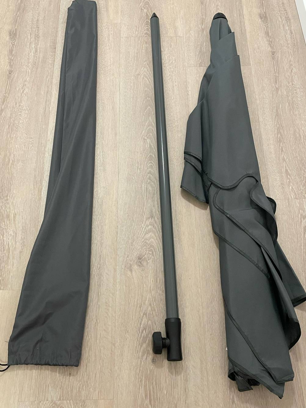 Im Test: Blick von oben auf einen auseinandergebauten Sonnenschirm knickbar neben der Aufbewahrungstasche.