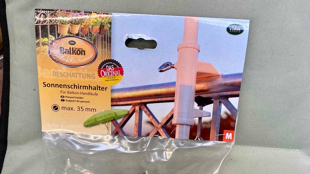 Nahaufnahme der Originalverpackung mit Informationen eines Sonnenschirmhalter-Balkongeländer.