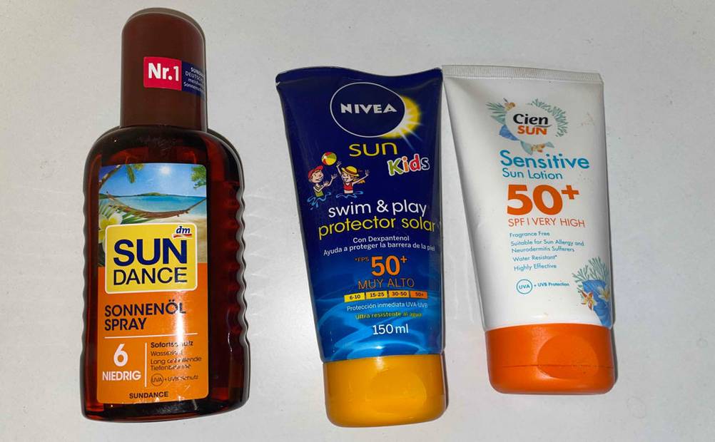 Ein Sonnenschutzmittel im Test: Drei verschiedene Sonnenschutzmittel liegen auf dem Boden. 
