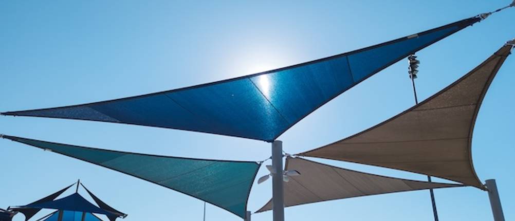 Dreieck-Sonnensegel-Test: Vier dreieckige Sonnensegel in unterschiedlichen Farben vor blauem Himmel.