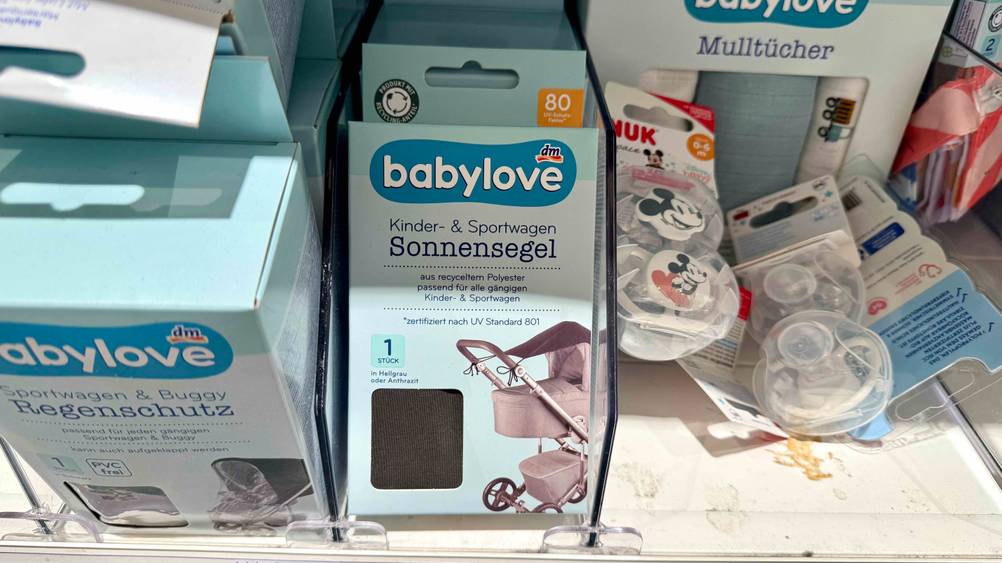 Sonnensegeln für Kinderwagen im Test: Mehrere Packungen in einem Verkaufsregal neben anderen Produkten.