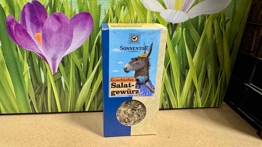 Eine Packung Sonnentor-Gewürze steht zum testen vor einem Blumenposter.