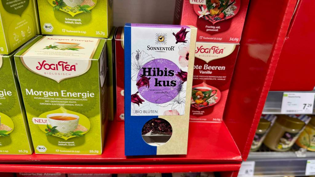 Hibiskustee im Test: Eine Verpackung mit losem Tee der Marke Sonnentor steht auf einem Verkaufsregal neben anderen Teesorten.