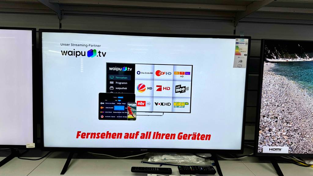 Sony Fernseher 43 Zoll im Test: Vor einem eingeschalteten Gerät liegen zwei Fernbedienungen.
