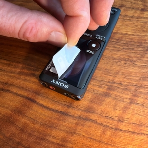 Eine Hand zieht eine Folie vom Display des Sony ICD-UX570B