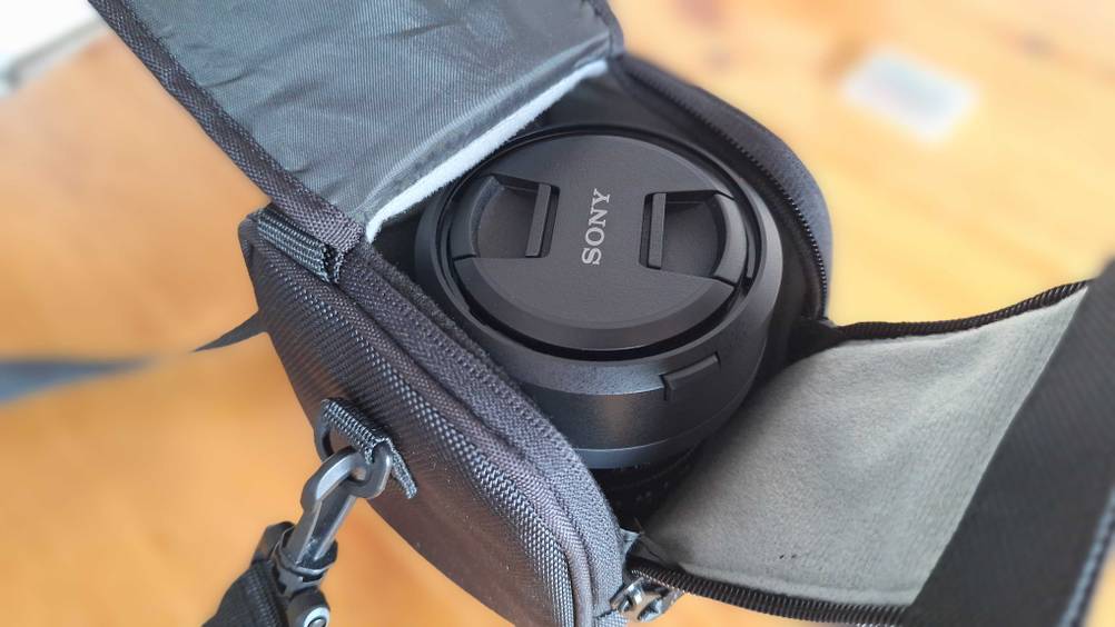 Getestet: Eine geöffnete Objektivtasche mit einem Objektiv im Inneren auf einer Holzfläche.