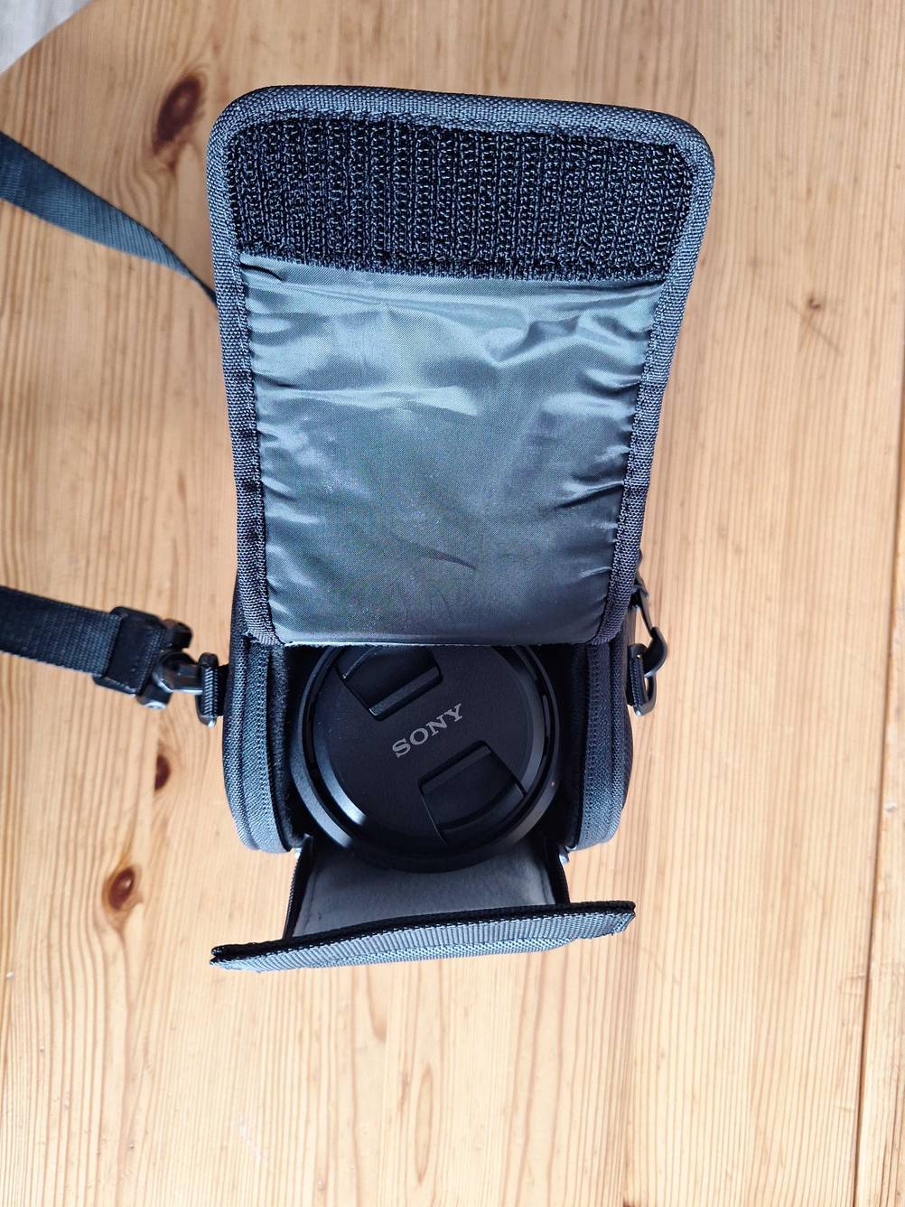 Objektivtasche getestet: Eine geöffnete Tasche mit Objektiv im Inneren von oben auf einer Holzfläche.