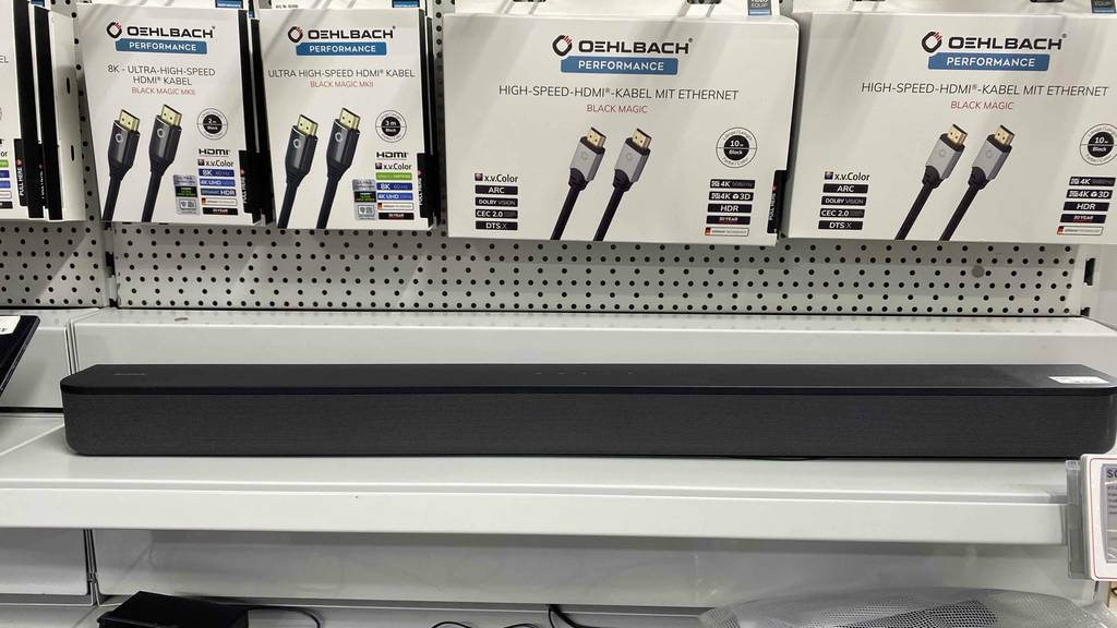 Sony-Soundbar-Test: Das graue längliche Modell steht auf einem Verkaufsregal. Oberhalb befinden sich verpackte HDMI-Kabel.