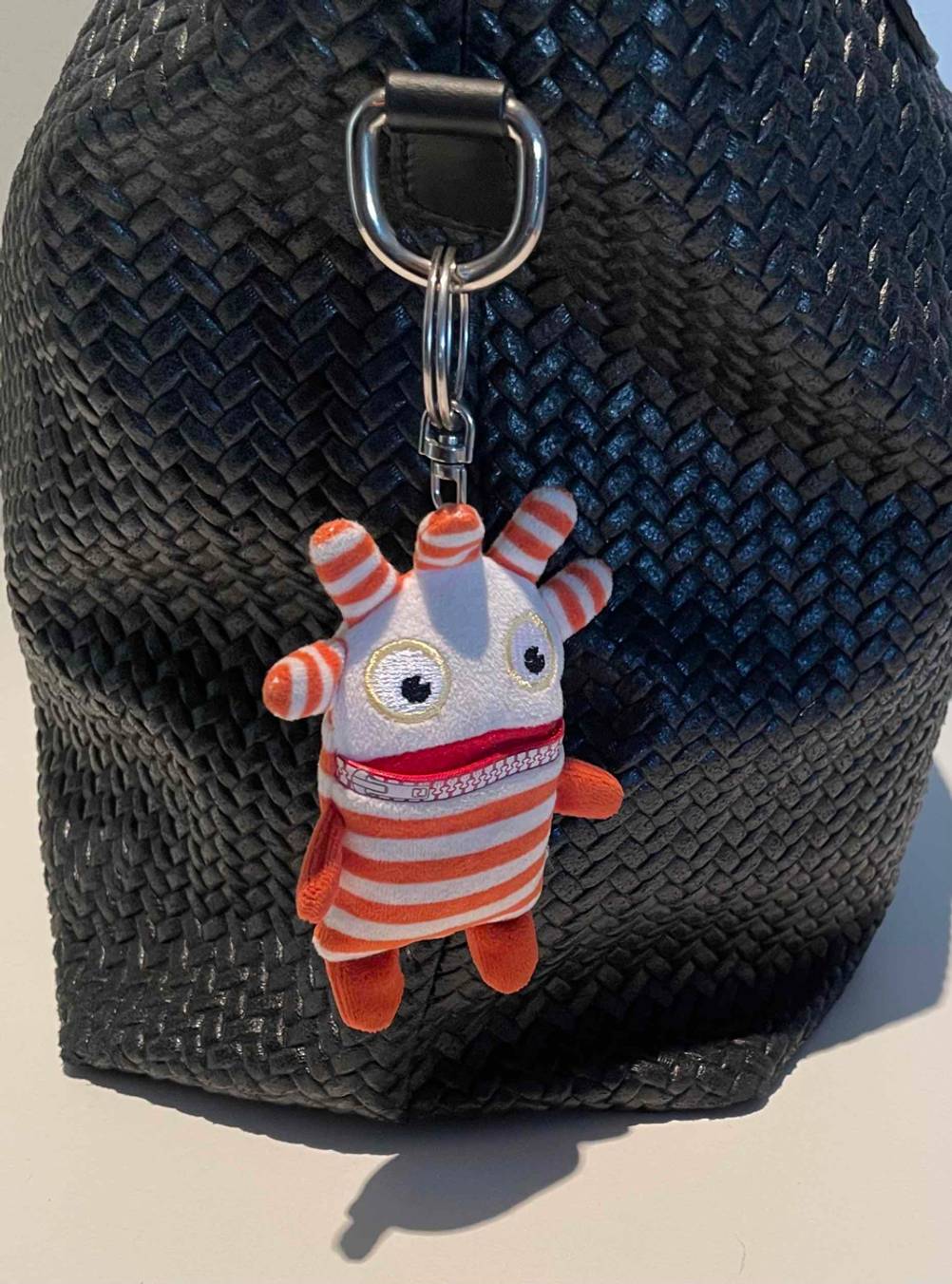 An einer dunklen Tasche an einer Öse hängt ein getesteter Sorgenfresser.