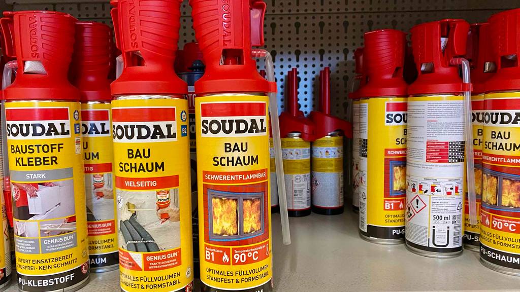 Mehrere Dosen des Bauschaumes im Test in einem Regal neben anderen Produkten.