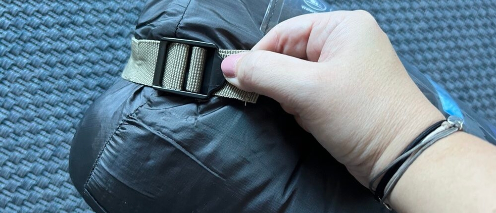 Schnalle zum Spannen des Tragegurts wird von Hand gehalten