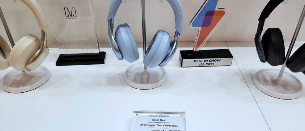 Noise-Cancelling-Kopfhörer im Test: drei Kopfhörer in verschiedenen Farben von Sound Core stehen nebeneinander auf einem weißen Regal