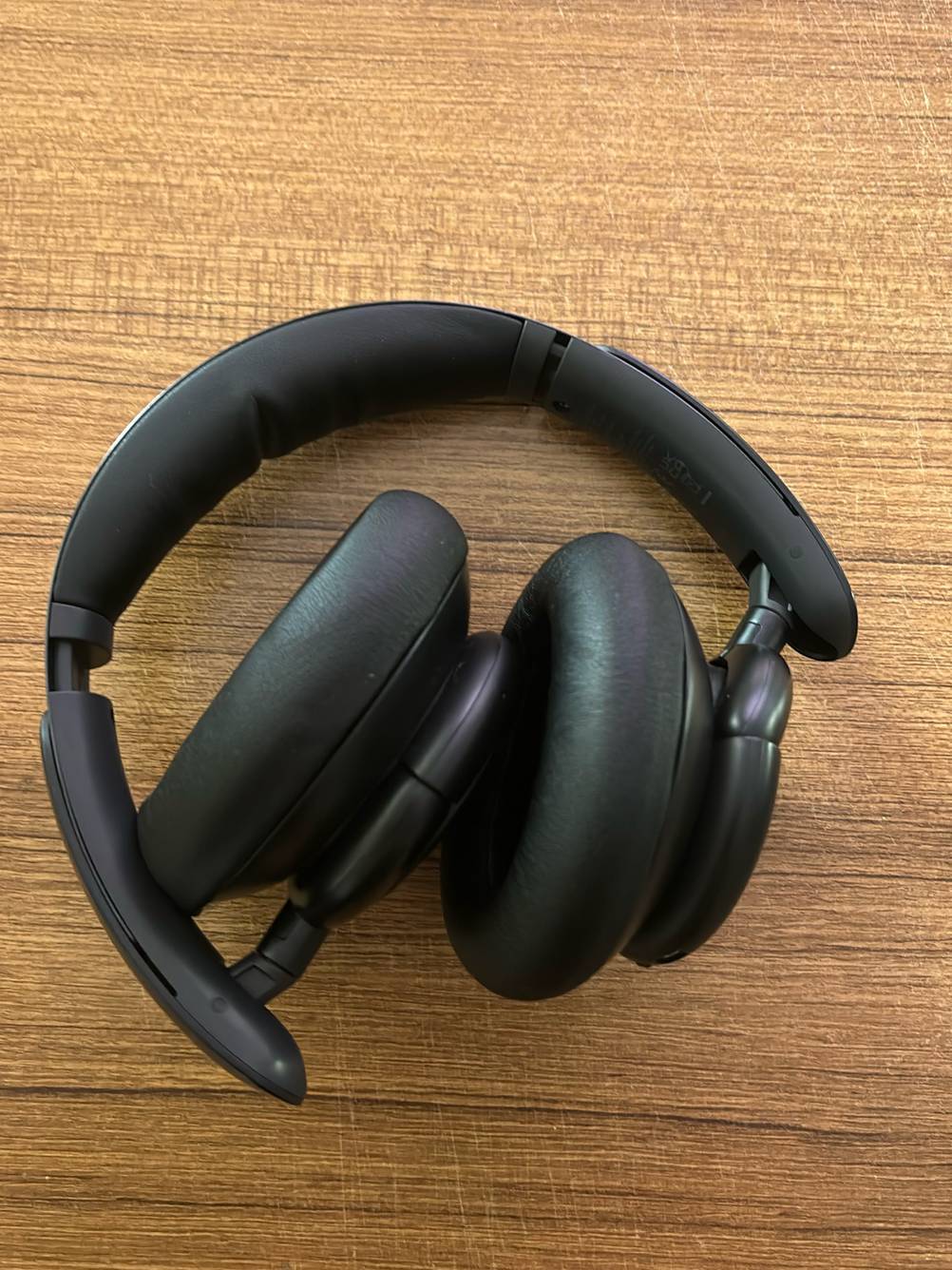 Ein ineinander zusammengerollter DJ-Kopfhörer liegt getestet auf einer Holzfläche.
