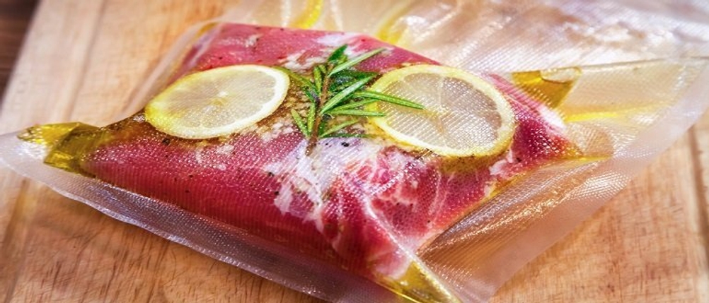 Fleisch, Zitronenscheiben und Kräuter in einem Vakuumbeutel