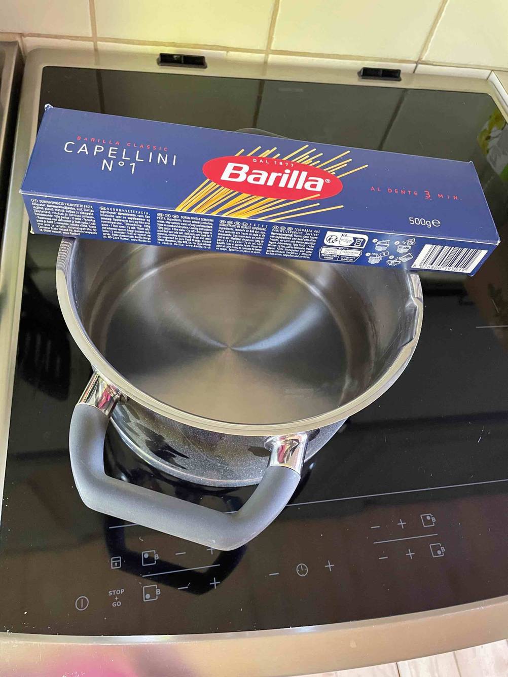 Spaghetti im Test: Eine Packung liegt auf einem Topf der auf dem Herd steht.