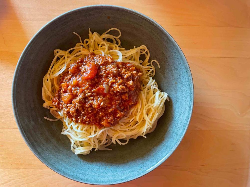 Spaghetti getestet: Ein Teller mit Spaghetti und Tomatensoße auf einem Holztisch.