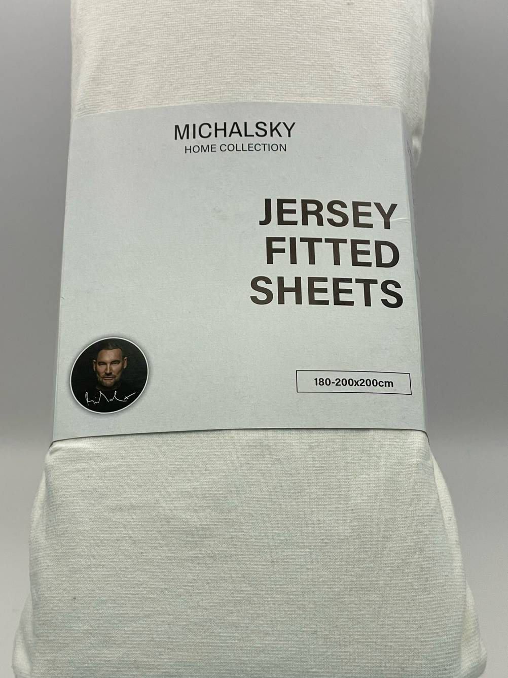 Geteset: Ein Spannbettlaken (180 x 200) in Verpackung mit Logo und Artikelbezeichnung vor einer hellen Fläche.