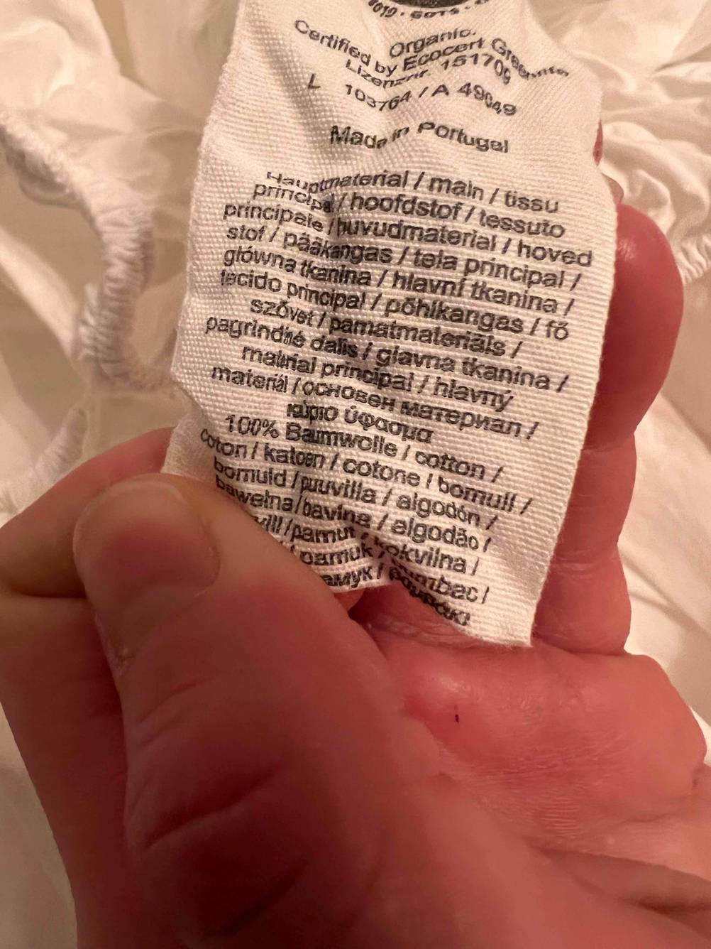 Spannbettlaken (200x200) getestet: Eine Hand hält das Label mit Informationen.