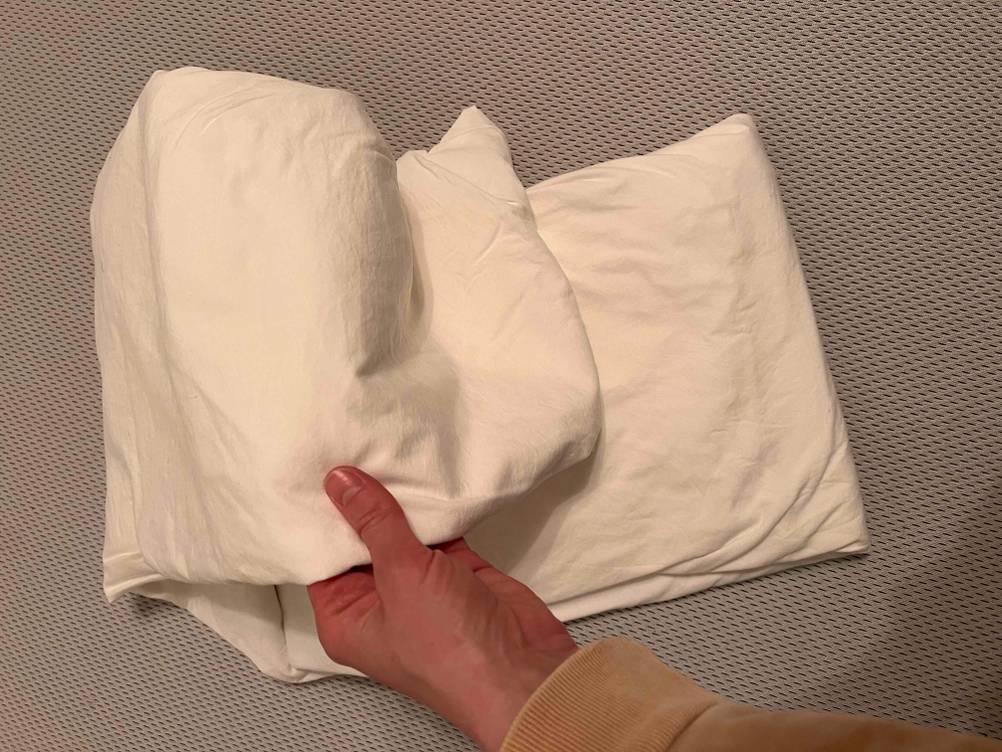 Eine Hand hält ein getestetes Spannbettlaken mit den Maßen 200x200 cm.