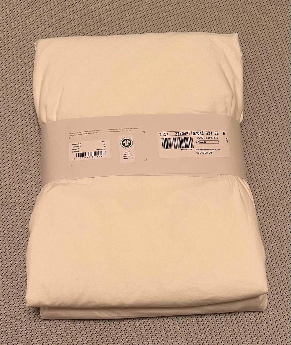 Ein getestetes Spannbettlaken mit den Maßen 200x200 cm liegt verpackt auf dem Boden. 