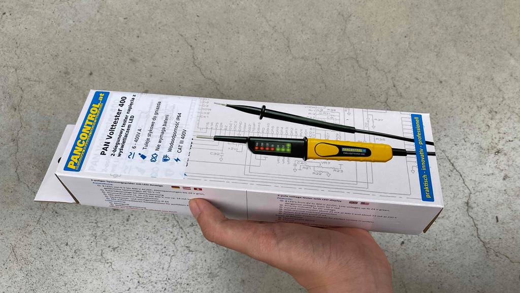 In der Hand befindet sich ein getesteter Spannungsprüfer. 