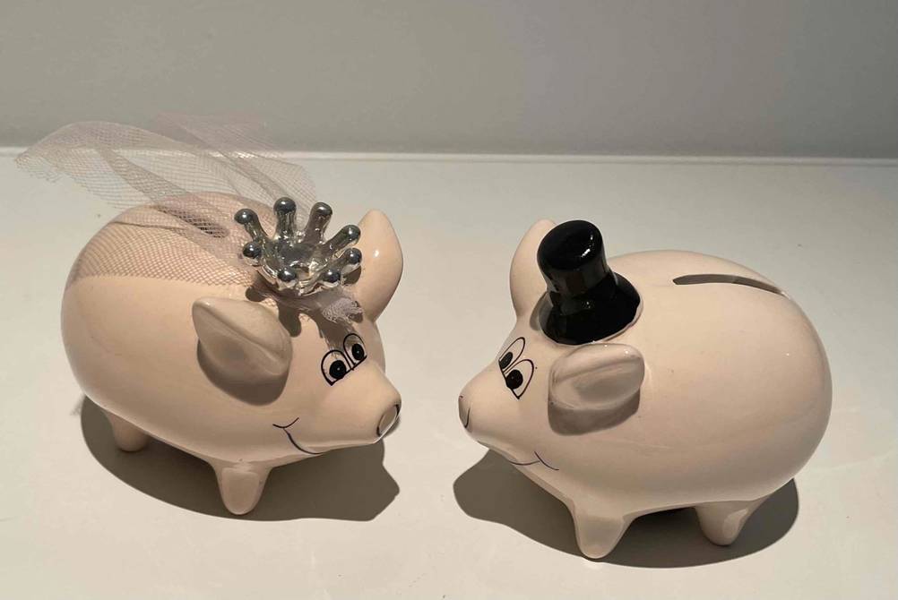 Sparschwein getestet: Zwei Sparschweine als Brautpaar auf einer hellen Fläche stehend.