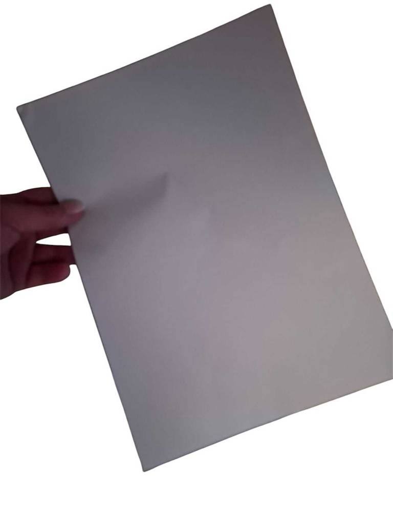 Eine Hand hält ein Blatt getestetes Druckerpapier 80 g vor einem weißen Hintergrund.