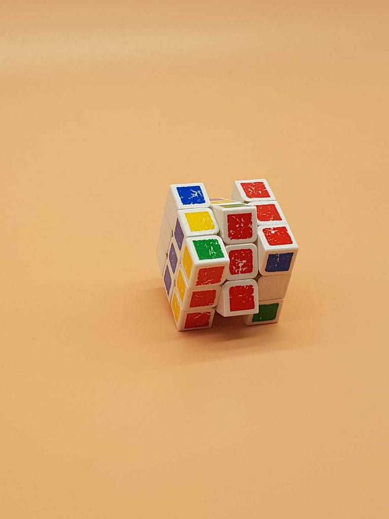 Ein Speedcube im Test weist mehrere gedrehte Ebenen mit verschiedenen Farben in einer Reihe auf und befindet sich auf einem pfirsichfarbenen Untergrund.
